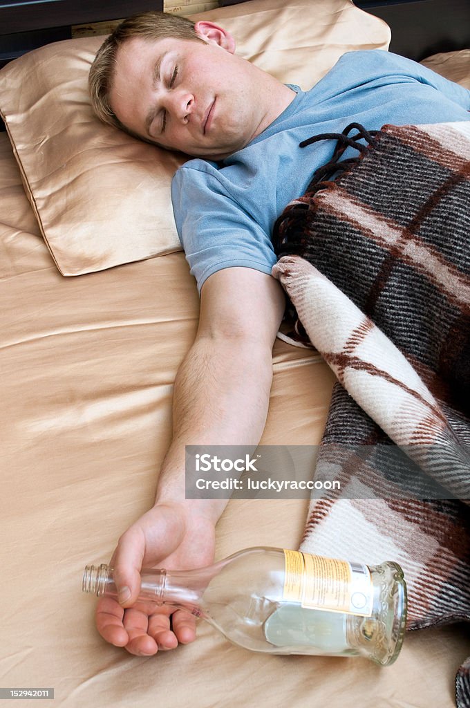 Giovane uomo che dorme con bottiglia di wiskey - Foto stock royalty-free di Abbigliamento casual