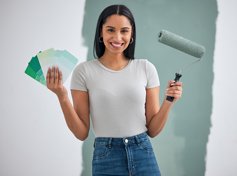 Color card, renovation and woman painting a house, home or apartment room wall green for maintenance. Artistic, designer and creative painter holding a roller and color palette with a happy smile
