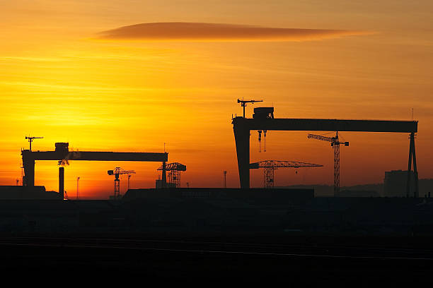 Belfast Shipyard Cranes Silhouette of the Belfast docks area at sunset including the iconic twin cranes of the shipyard. belfast stock pictures, royalty-free photos & images
