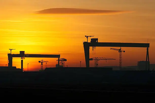 Silhouette of the Belfast docks area at sunset including the iconic twin cranes of the shipyard.