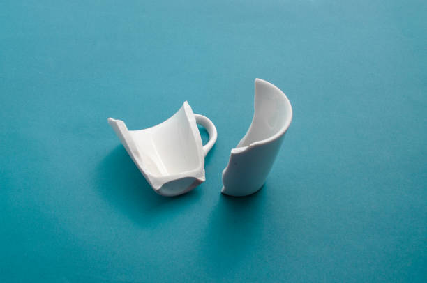 istock Closeup of a broken cup on a blue surface, showing its fragility and imperfection. 1529453539