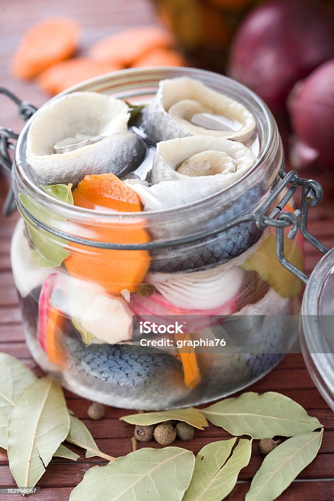 Pickled herring in a jar on a table Pickled Herring in glass jar Carrot Stock Photo