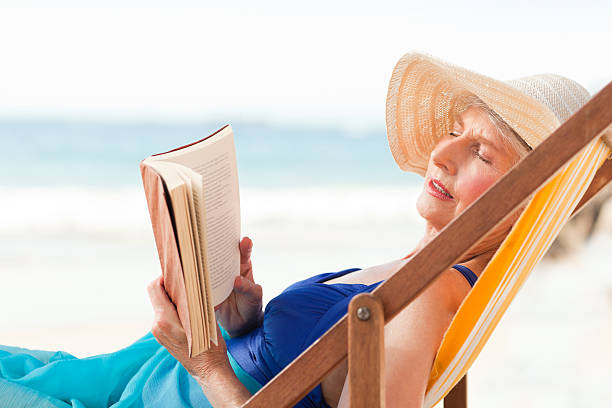 istock Elderly woman reading a book at the beach 152946376