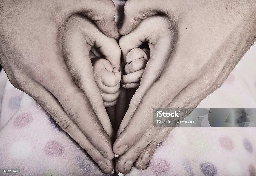 Family Heart with Hands- cross-processed A family of hands form a heart - father on the outside, then mother's hands and infant baby hands in the middle.  cross-processed and desaturated for dramatic effect Adult Stock Photo