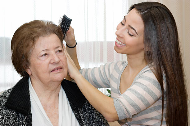 Granddaughter brushing her grandmother's hair Beautiful granddaughter combing the hair her grandmother. human hair women brushing beauty stock pictures, royalty-free photos & images