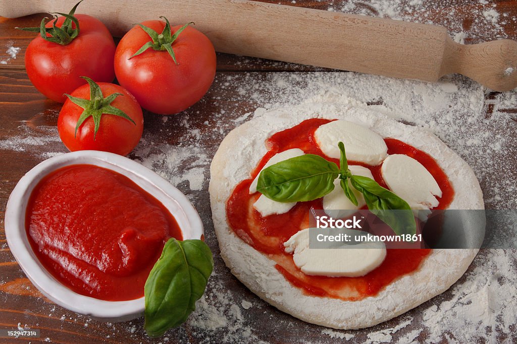 Pizza Preparation Making pizza - Raw pizza and ingredients on a wooden table Basil Stock Photo