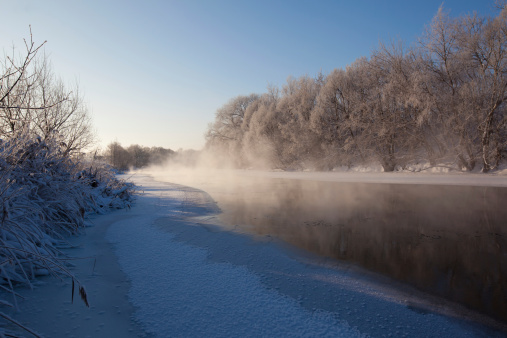 Half frozen river with mist in the
