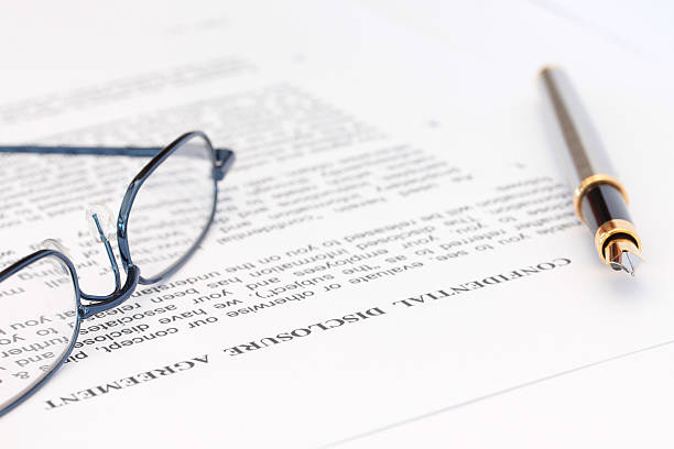 Fountain pen and blue spectacles resting on top of disclosure agreement