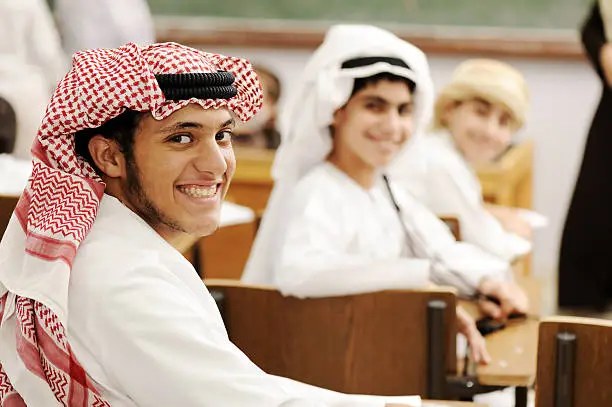 Photo of Group of Arabic students with eastern traditional clothes in classroom.