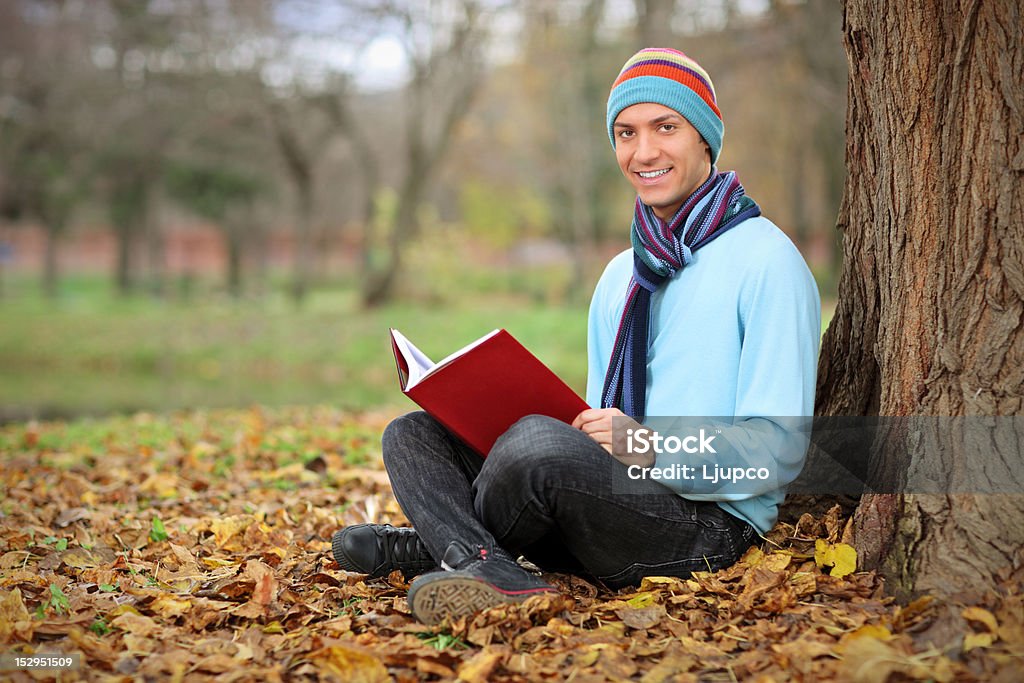Jeune homme souriant lisant un livre - Photo de Accessoire vestimentaire pour le cou libre de droits
