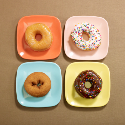 Overhead of Four Doughnuts on sqaure plates