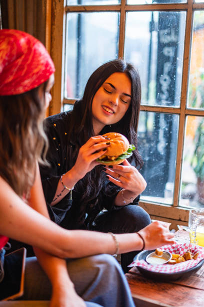 Customer aged between 20-30 years old is satisfied with his hamburger in a restaurant