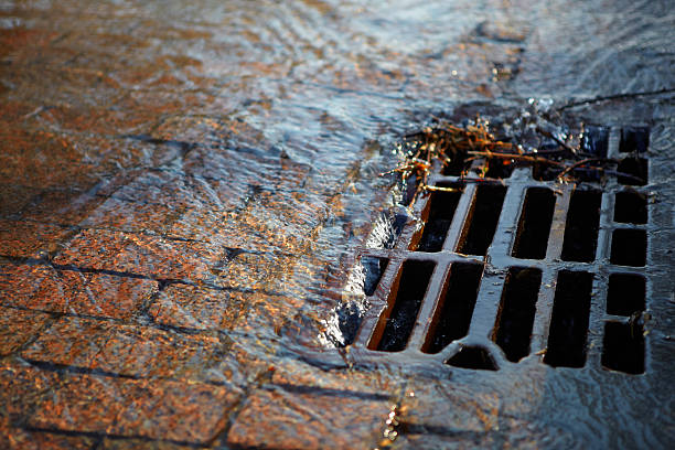 Water flows into the hatch on a spring sunny day Melted water flows down through the manhole cover on a sunny spring day manhole stock pictures, royalty-free photos & images