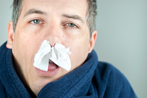 Close-up of a man with tissue in his nose.