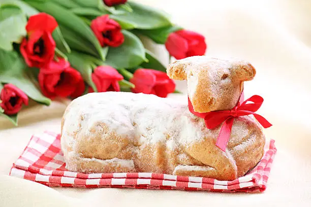 Easter lamb cake and red tulips on white background