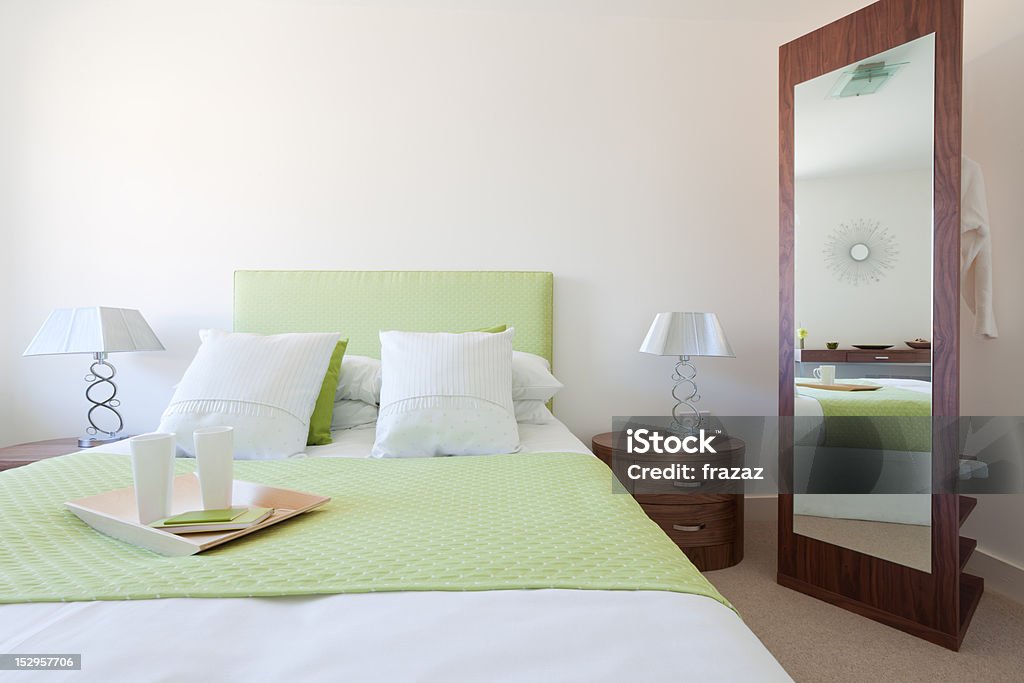 Modern Bedroom suite Modern bedroom suite with lime green quilt and headboard, white duvet and pillows, side tables with lamps and mirror Apartment Stock Photo