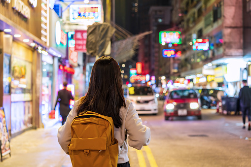 Young woman traveler walking in the Mong Kok night market in Hong Kong