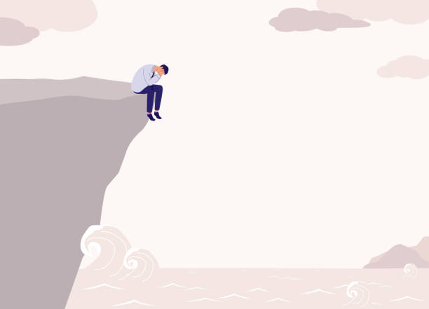 istock Desperate Businessman Sitting On The Edge Of The Mountain Cliff Is About To Commit A Suicide. 1529607918