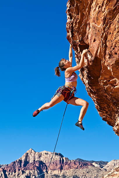 istock Female rock climber clinging to a cliff. 152963271