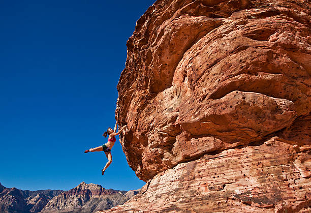 istock Female rock climber clinging to a cliff. 152963513