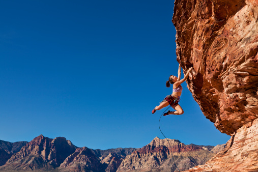Hembra rock climber aferrando al un acantilado. photo