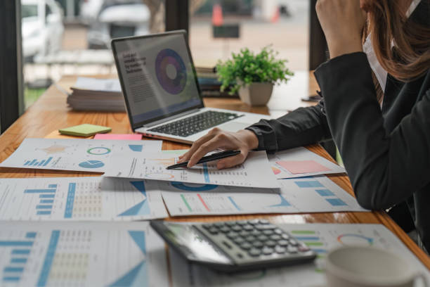 istock Asian Businesswoman Using laptop computer and working at office with calculator document on desk, doing planning analyzing the financial report, business plan investment 1529636595