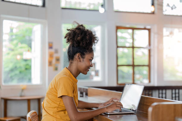 istock Young african american female working and typing on laptop computer with blank screen while sitting on a sofa at home 1529637832
