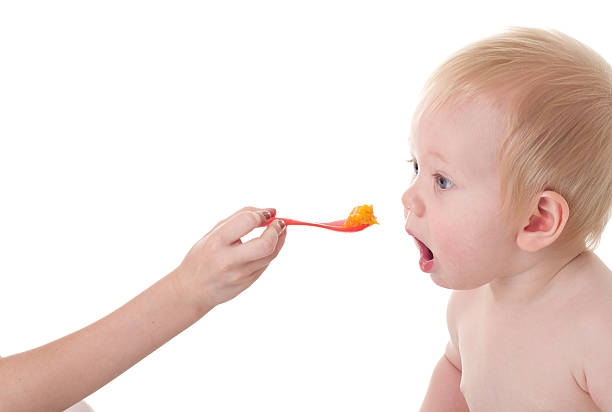 Baby opening mouth for spoonful of food stock photo