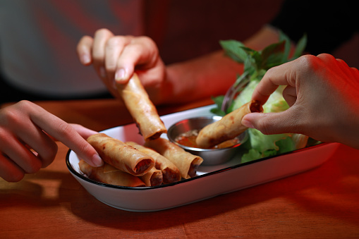 Close-up shot of a small group of friends enjoying Vietnamese spring rolls