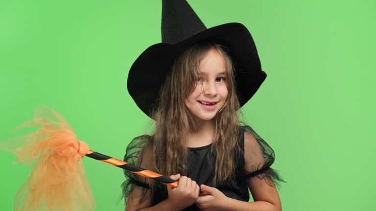 Studio shot portrait of a beautiful child girl in witch costume on green background