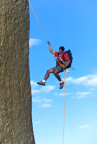 Rock climber rappells from the summit after a successful ascent.