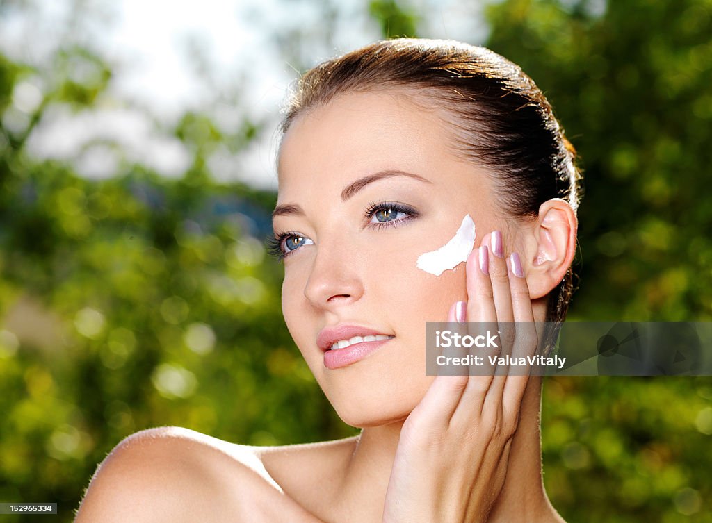 Hermosa mujer aplicar crema en mejilla - Foto de stock de 20 a 29 años libre de derechos