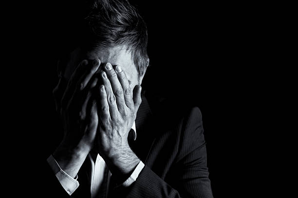 Desperate businessman covering his face.