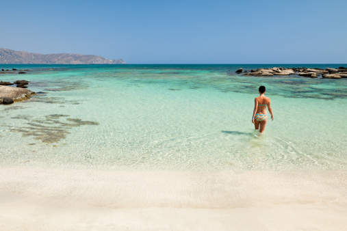 Young woman bathing in beautiful Elafonisi beach with turquoise sea. (Crete, Greece)