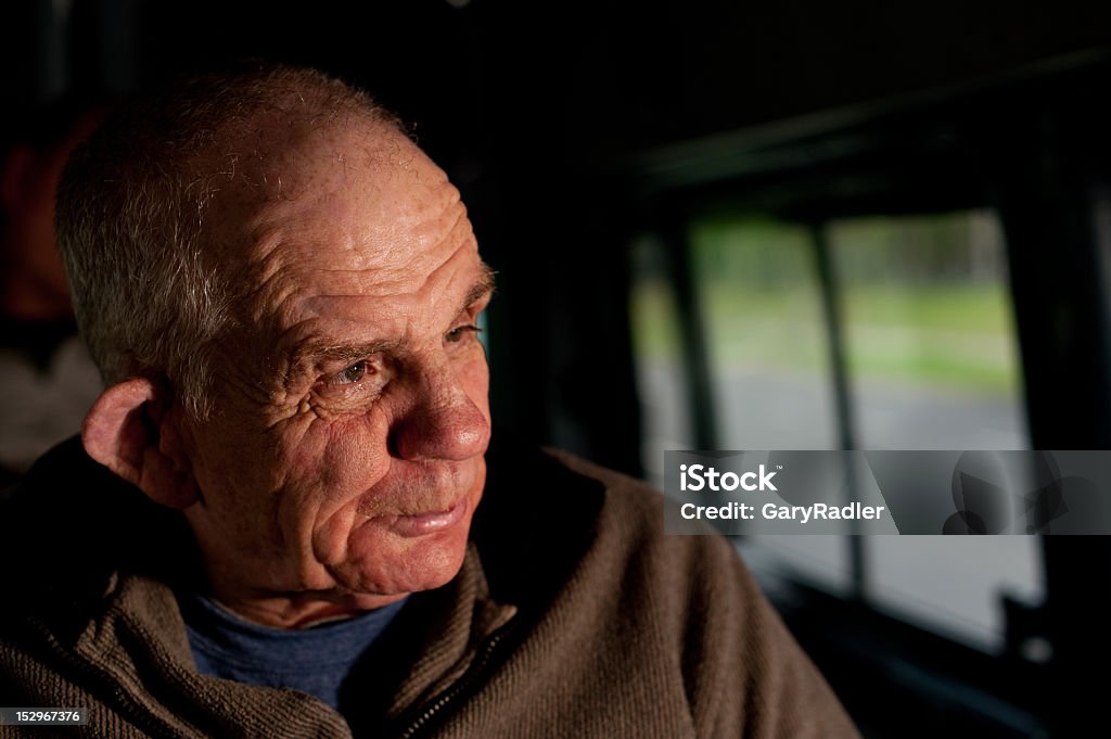 Sixty-six year old man with a disability in bus Sixty-six year old man with a disability in bus.  A low key image made with a hand held off-camera flash, gelled to give the appearance of evening sunlight.  A fast shutter speed was set to darken the background. Senior Adult Stock Photo