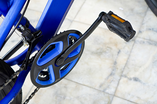 The photo shows the front derailleur, pedal and chain of a kids mountain bike for exercise.