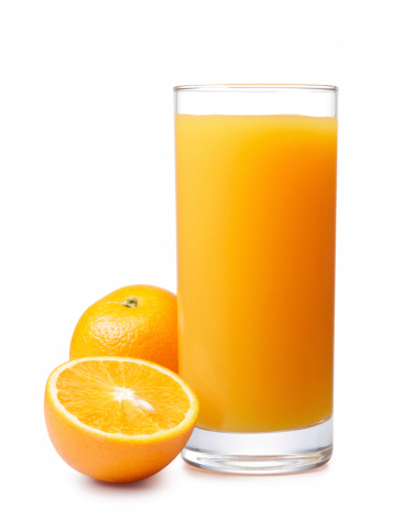 Glass of orange juice with half oranges on vintage table