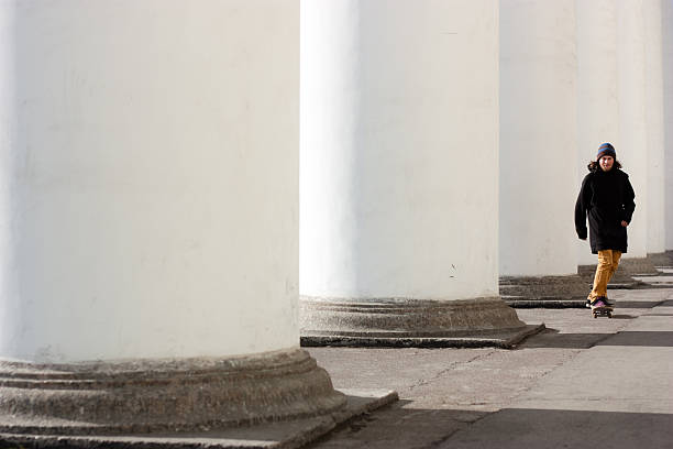 skater riding next to columns stock photo