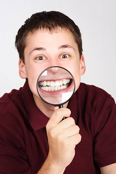 istock man holding magnifier and showing teeth through it 152973961