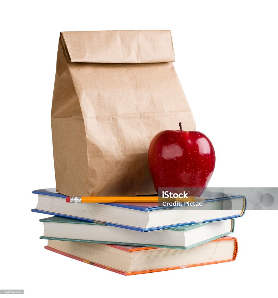 School lunch on top of a pile of books Lunch bag with apple and pencil on top of books. School Lunch Stock Photo