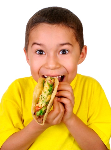 Hispanic boy eating a Mexican taco, isolated on white background