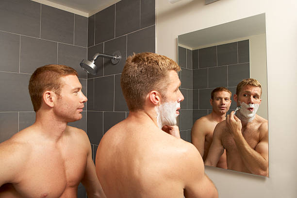 Two gay men shave together in a bathroom stock photo