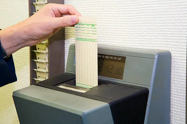 A worker is punching his time card with the automatic clock