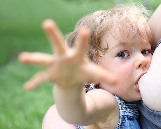 Child breastfeeding outdoors and reaching towards camera stock photo