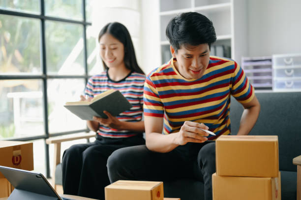 istock Starting small businesses SME owners, two check online orders Selling products working with boxs freelance work  on sofa at home using tablet and laptop  marketing, packaging, concept 1529802410