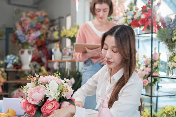 色とりどりの花屋で働く2人の女性花屋のパートナー。 - flower arranging ストックフォトと画像