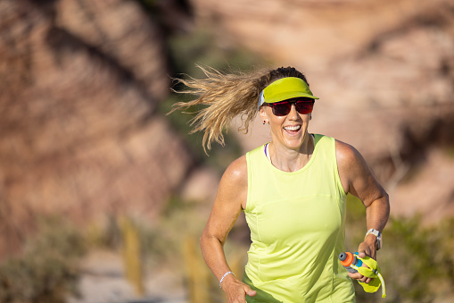A healthy woman in her 50's cross country running through the desert landscape of Las Vegas, Nevada