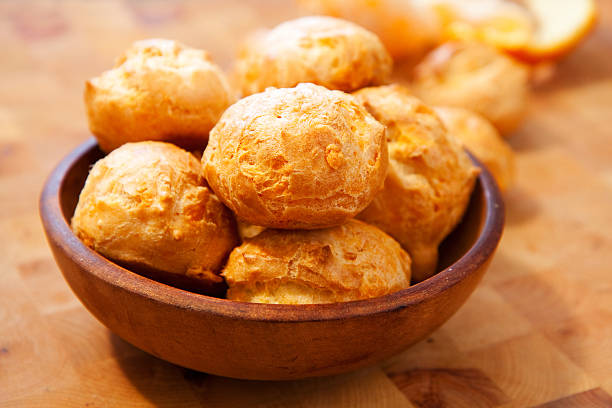 Bowl of cheese gougeres on table Freshly made cheese gougeres on wood cutting board choux pastry photos stock pictures, royalty-free photos & images