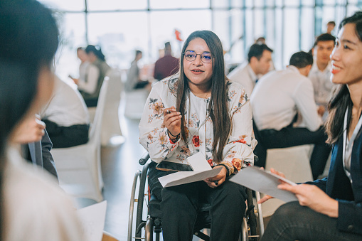 Asian Indian disabled woman in wheelchair participate in business conference workshop leading discussion
