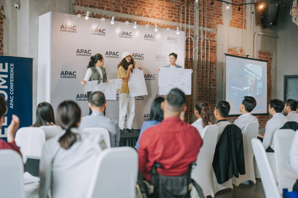 istock Team building asian group presenting ideas in front of all workshop participants in APAC business conference discussion 1529813437
